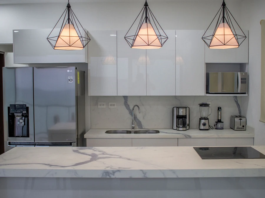 Marble kitchen with geometric pendant lighting and full-height backsplash